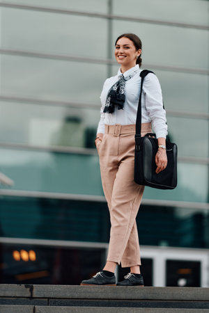 Smiling Latina businesswoman strides confidently through urban streets.の写真素材