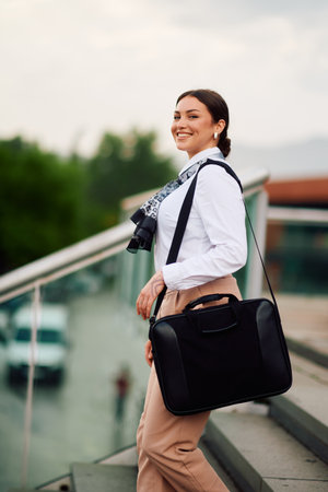 Smiling Latina businesswoman strides confidently through urban streets.の写真素材