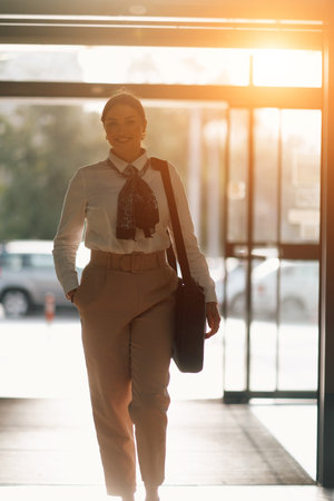 Empowered Latina businesswoman strides confidently through modern office.の写真素材