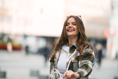 Charming Woman Strolls Through the City in a Stylish Plaid Shirt, Blue Pants, and Sunglasses.の写真素材