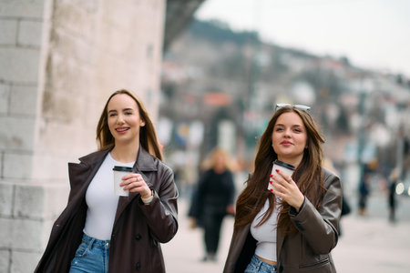 Two beautiful business women go to work while holding cups of coffee in their handsの写真素材