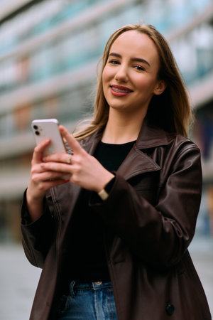 Business Woman With Phone Near Office. Portrait Of Beautiful Smiling Female In Fashion Office Clothes Talking On Phone While Standing Outdoors. Phone Communication.の写真素材