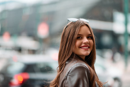 Charming Woman Strolls Through City Streets Wearing a Fashionable Leather Jacket.
