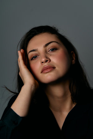 Portrait Of A Thoughtful Woman In Soft Lighting, Relaxed Hand Supported Pose For Studio Headshot
