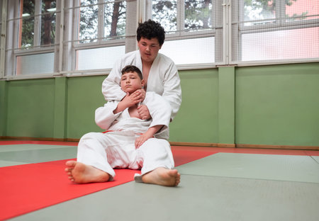 Two young athletes show their judo skills in front of the coaches