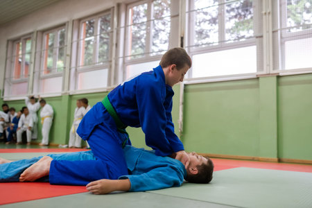 Two young athletes show their judo skills in front of the coaches