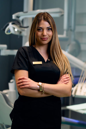 Confident Female Dental Professional In Black Scrubs Standing With Arms Crossed In A Modern Clinicの写真素材