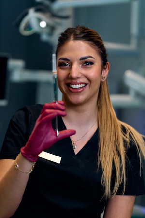 Smiling Female Medical Professional Holding Syringe in a Modern Clinic Setting for Patient Careの写真素材
