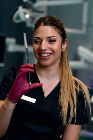 Friendly Female Nurse Preparing Syringe for Injection in a Modern Clinic Setting, Smilingの写真素材