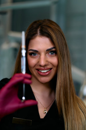 Confident Medical Professional Woman Smiling With Syringe In Hand In Clinic Settingの写真素材