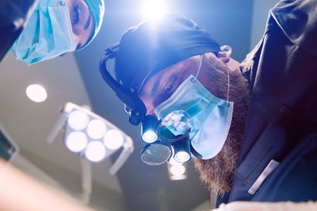 Surgeon With Headlamp and Mask Performing a Complex Operation in the Operating Room