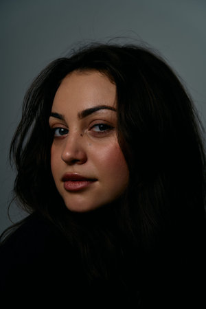 Portrait Of A Calm Woman With Dark Hair In Soft Studio Lighting For Editorial Use