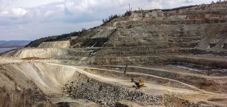 Yellow excavator inside an open cast mine. Large quarry of minerals and rocks.の写真素材