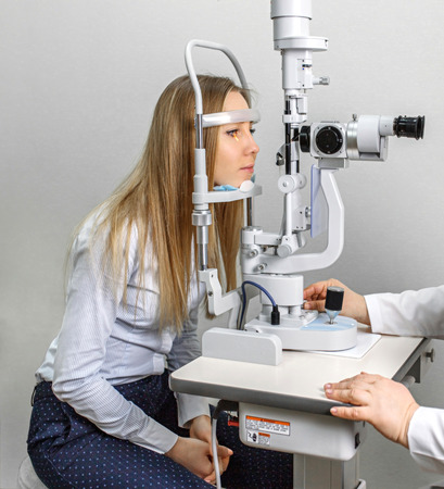 Attentive optometrist examining female patient on slit lamp in ophthalmology clinicの写真素材