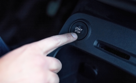 Driver hand pushes engine start stop button. Modern luxury car interior detailsの写真素材