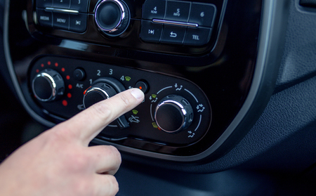 male hand pressing button in modern car. Man adjusts the temperature of the car air conditionerの写真素材