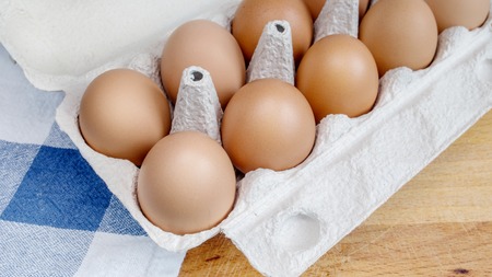 Packing eggs in a cardboard box from above and close-up on a wooden boardの写真素材