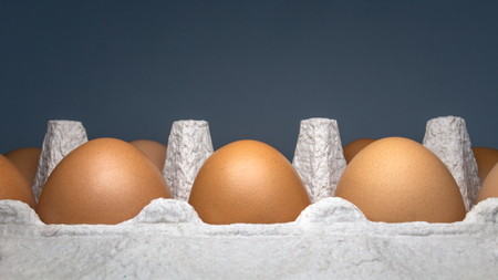 Packing eggs in a cardboard box on the side and close-up on a dark backgroundの写真素材