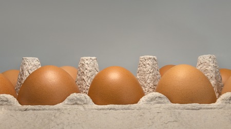 Packing eggs in a cardboard box on the side and close-up on a gray backgroundの写真素材