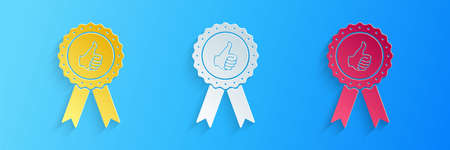 Paper cut Thumbs up on medal badge with ribbons icon isolated on blue background. Paper art style....