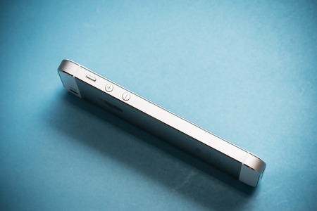 Bangkok, Thailand- October 4, 2015: The gold Apple iPhone 5s on blue paper background and iPhone 5s designed and developed by Apple Inc., it was released on September 20, 2013のeditorial素材