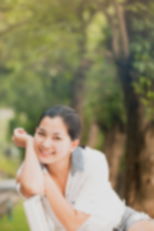 Blur effect of young asian woman relaxing outdoors looking happy and smiling