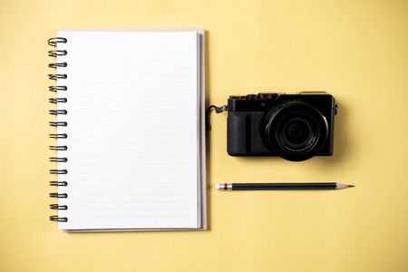 Flat lay style of empty book and pencil and retro camera with yellow pastel background and copy space for design work concept travelの写真素材