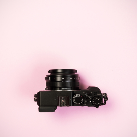 Vintage digital compact camera on pink pastel color background with flat layout and copy space for design workの写真素材
