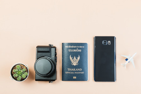 Flat lay and copy space for design work of vintage digital compact camera with Thailand official passport, smart phone, small cactus and small airplane on yellow pastel color background.の写真素材