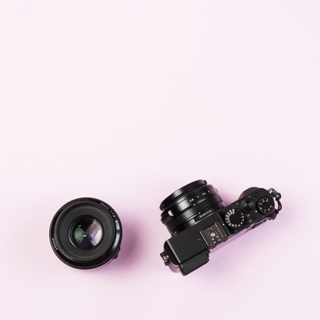 Vintage digital compact camera and fix lens 50mm on pink pastel color background with flat layout...