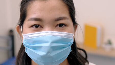 Portrait of an Asia young female who is wearing a face shield with mask rounded around her face from a frontal perspective to protect her glasses and eyes prepare to new normal. Coronavirus pandemic.の写真素材