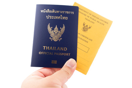 Hand holding Thailand official passport and vaccine passport are on isolated white background with a clipping path.の写真素材