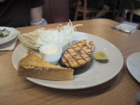 Savory grilled salmon dish with sides restaurant dining culinary presentation casual environment close-up view gourmet experienceの写真素材