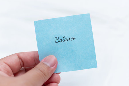 Hand holding note with text 'balance' indoor setting lifestyle concept minimalist environment close-up viewpointの写真素材