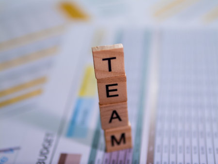 A close-up view of wooden blocks spelling 'TEAM' a business report symbolizing teamwork in an office.の写真素材