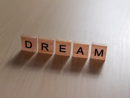 A close-up of wooden blocks spelling DREAM in a minimalist setting inspiring creativity and motivation.の写真素材