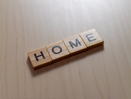 Discover how simple wooden tiles create a warm inviting atmosphere spelling 'HOME' in minimalist style.の写真素材