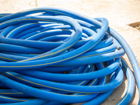 A vibrant blue garden hose lies coiled ready for use in outdoor gardening tasks.の写真素材
