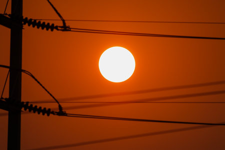A stunning sunset casts a warm glow over urban power lines creating a serene and captivating view.の写真素材