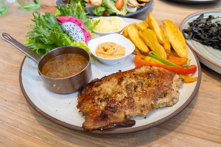 Savor a beautifully presented grilled chicken dish served with fresh sides in an inviting restaurant.の写真素材