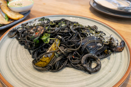 Discover the artistry behind an exquisite black pasta dish served in a chic restaurant.の写真素材