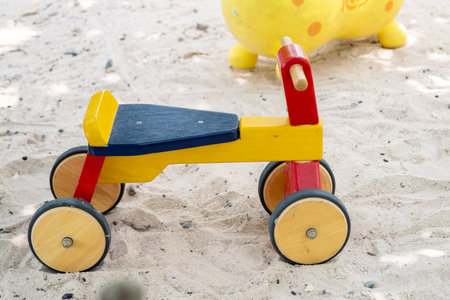 A vibrant wooden toy vehicle rests the sandy beach inviting children to explore and play.の写真素材
