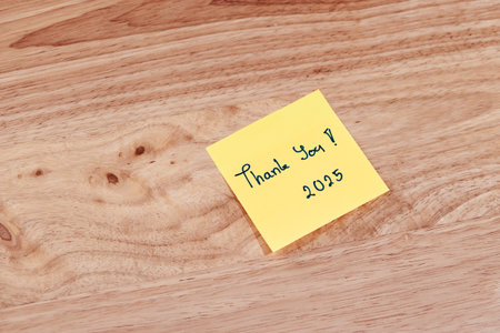A heartfelt Thank you 2025 note captures a moment of appreciation a warm wooden surface.