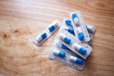 A close-up image of blue and white capsules a wooden table symbolizing health and wellness.
