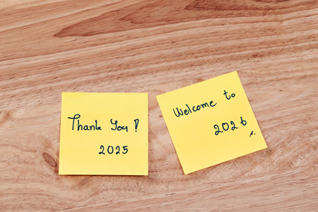 Sticky notes express gratitude for Thank you 2025 and Welcome to 2026 sticky notes symbolizing hope and fresh starts in a warm workspace.の写真素材