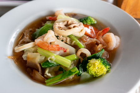 A vibrant seafood stir-fry featuring fresh ingredients beautifully plated in a cozy restaurant setting.の写真素材