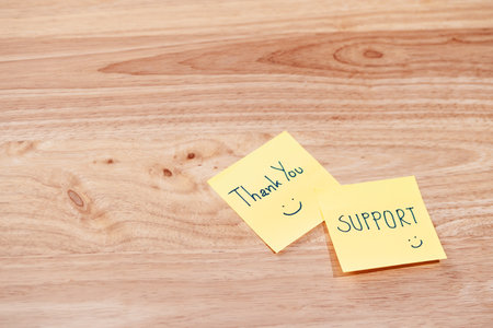Two sticky notes expressing gratitude for support in a warm office setting.の写真素材