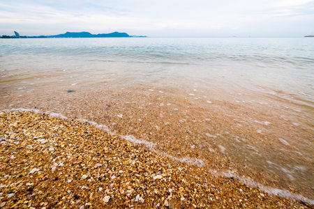 A serene coastal view showcasing gentle waves lapping against a sandy shore capturing tranquility.