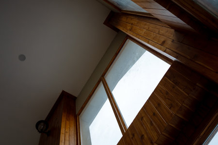A creative view of wooden window frames capturing natural light in a cozy interior space.の写真素材