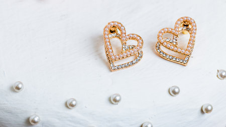Delicate heart-shaped earrings adorned with jewels placed a cake for a romantic celebration.の写真素材